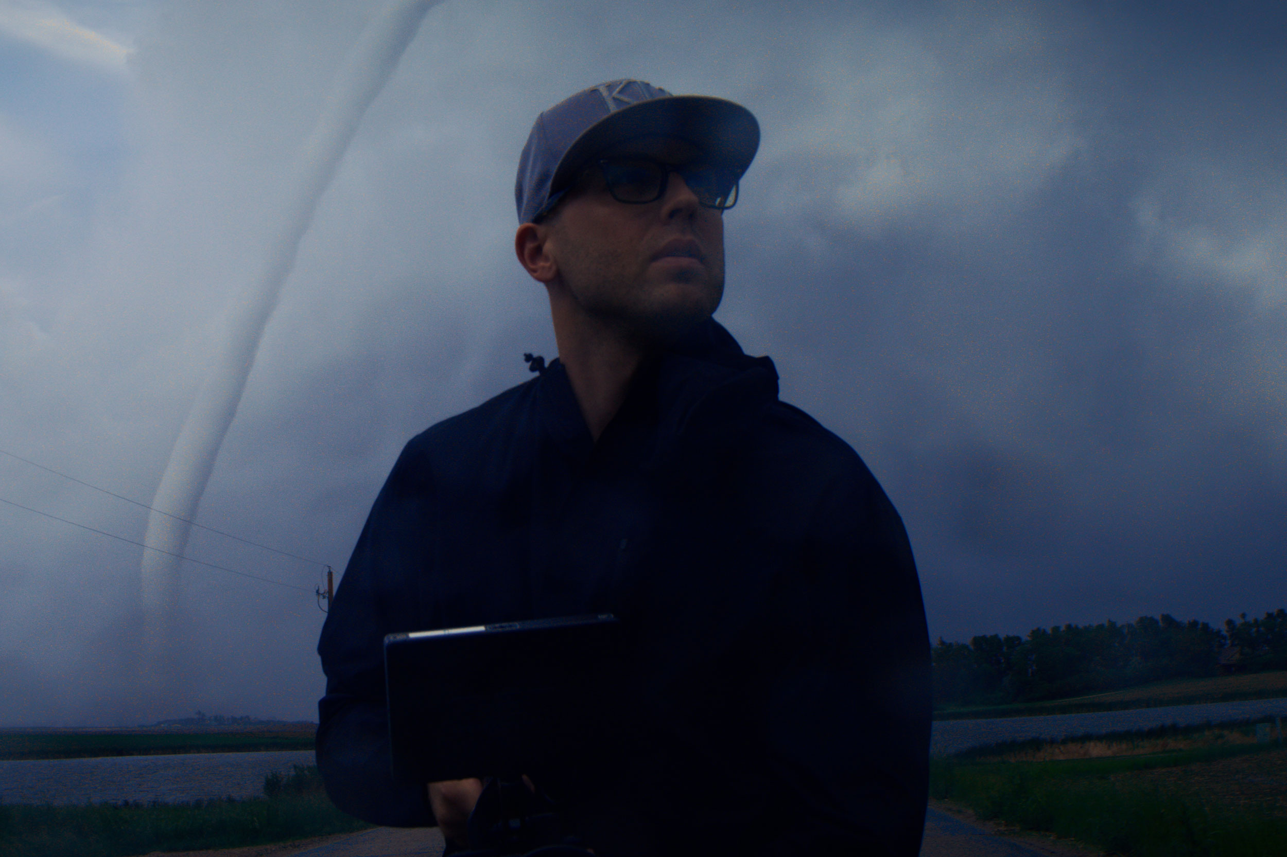 Dorion Antares standing in the field beneath a tornado