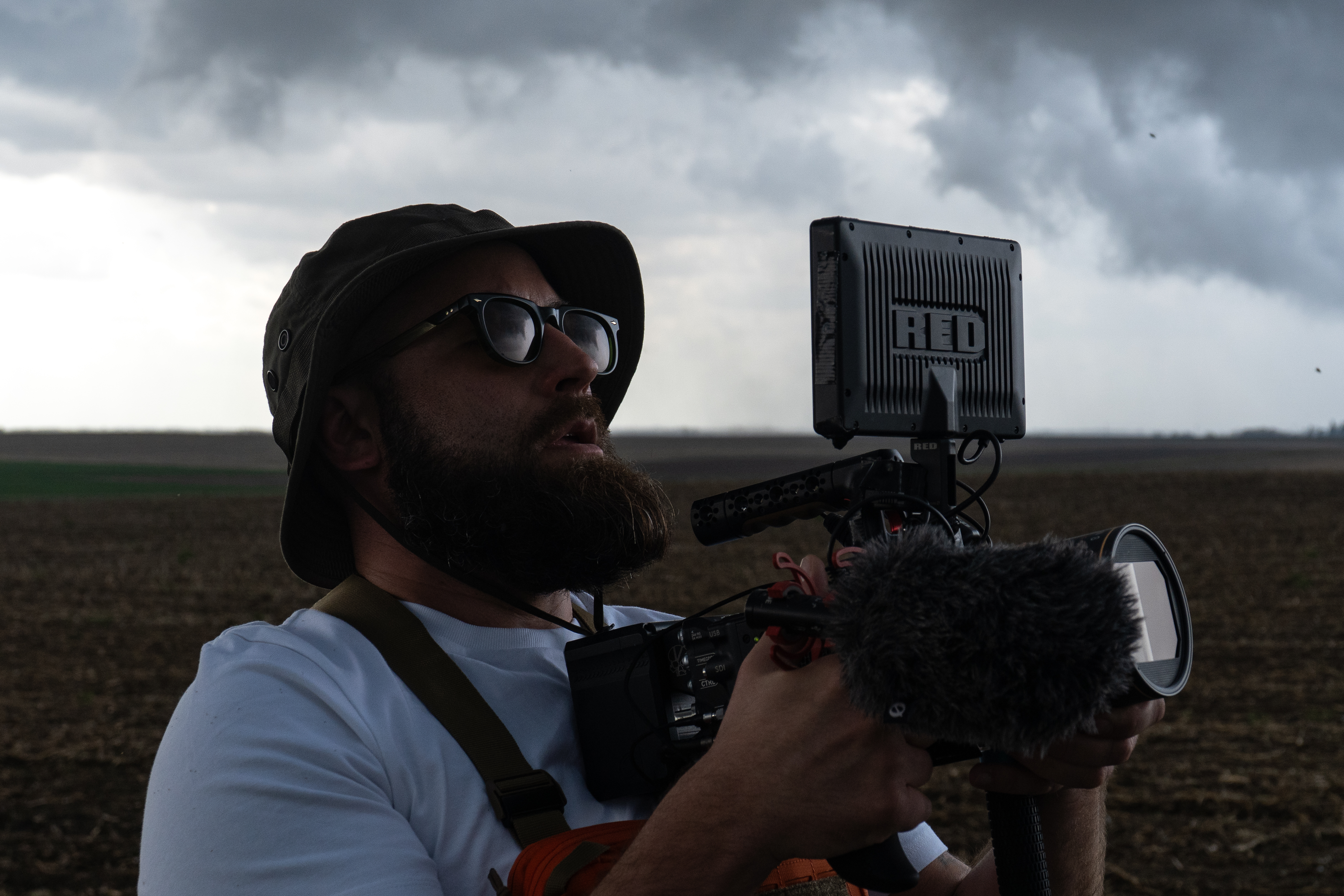 Stephen Brucher filming in the field under storm clouds